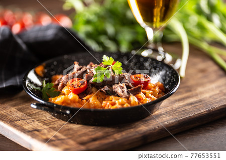 Tomato sauce gnocchi with sous-vide beef and fresh tomatoes served in a dark plate Tomato sauce gnocchi with sous-vide beef and fresh tomatoes served in a dark plate 77653551