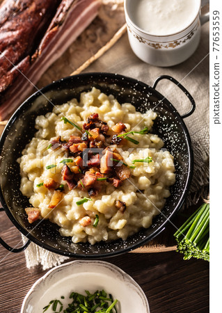 Top view of typical Slovakian food halusky with bryndza cheese, topped with bacon and chives 77653559