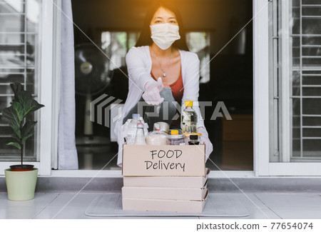 Woman holding takeaway food from delivery service during coronavirus pandemic situation at home Woman holding takeaway food from delivery service during coronavirus pandemic situation at home 77654074