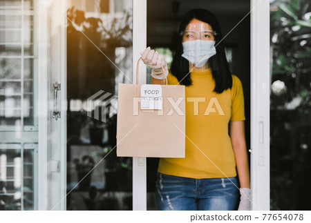 Woman hands holding takeaway food in paper bag from delivery service during coronavirus pandemic situation at home 77654078