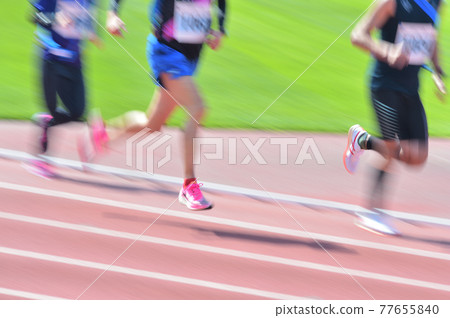 Track and field runners running on tracks are captured with a slow shutter 77655840