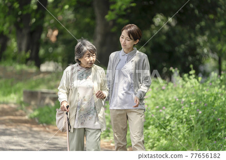 Senior woman and caregiver taking a walk in the park 77656182