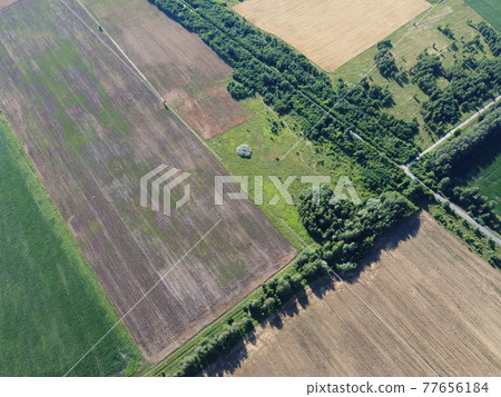 Crossroads of two roads among farm fields, aerial view. Agrarian landscape, bird's-eye view. Crossroads of two roads among farm fields, aerial view. Agrarian landscape, bird's-eye view. 77656184