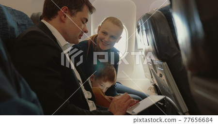 Busy father, child and mother traveling by plane 77656684