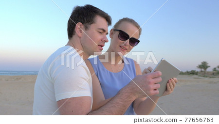 Young people taking pictures of sunset on the shore 77656763