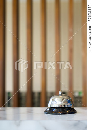 Silver service bell on hotel reception desk. Close up 77658351