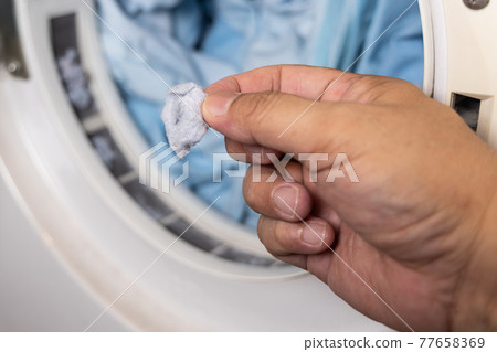 Hand removing lint from fabric trapped on laundry dryer filter Hand removing lint from fabric trapped on laundry dryer filter 77658369