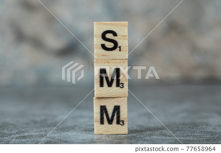 SMM writing with black letters on wooden dices on blurred background SMM writing with black letters on wooden dices on blurred background 77658964