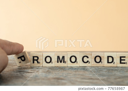 Promocode writing with black letters on wooden dices on the coral background Promocode writing with black letters on wooden dices on the coral background 77658987