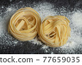 Raw nest noodles with flour on a dark background 77659035