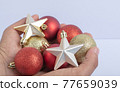 Holding christmas tree balls and stars in the hand 77659039