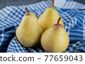 Juicy yellow pears on blue checked kitchen towel 77659043