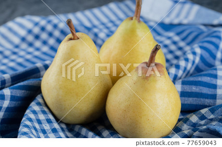 Juicy yellow pears on blue checked kitchen towel 77659043