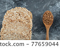 Airy crispbread and wooden spoon of raw buckwheat on marble surface 77659044