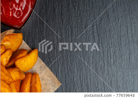 Rustic potato with ketchup on slate, black stone dishes. Top view. 77659648