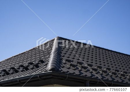 Brown corrugated metal profile roof installed on a modern house. The roof of corrugated sheet. Roofing of metal profile wavy shape. Modern roof made of metal. Metal roofing. 77660107