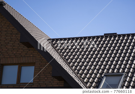 Brown corrugated metal profile roof installed on a modern house. The roof of corrugated sheet. Roofing of metal profile wavy shape. Modern roof made of metal. Metal roofing. Brown corrugated metal profile roof installed on a modern house. The roof of corrugated sheet. Roofing of metal profile wavy shape. Modern roof made of metal. Metal roofing. 77660118
