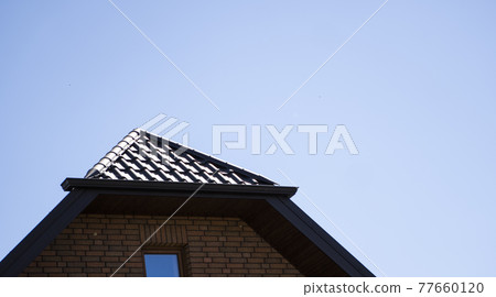 Brown corrugated metal profile roof installed on a modern house. The roof of corrugated sheet. Roofing of metal profile wavy shape. Modern roof made of metal. Metal roofing. Brown corrugated metal profile roof installed on a modern house. The roof of corrugated sheet. Roofing of metal profile wavy shape. Modern roof made of metal. Metal roofing. 77660120