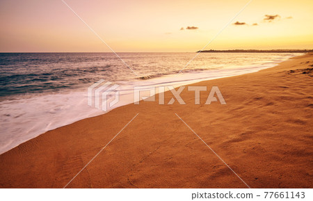 Tropical sandy beach with motion blurred waves at sunset, color toning applied. Tropical sandy beach with motion blurred waves at sunset, color toning applied. 77661143