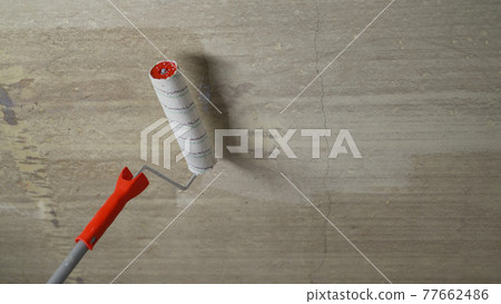 Working primer with a ceiling paint roller. Close-up of concrete priming process. Priming the ceiling with a roller. Working primer with a ceiling paint roller. Close-up of concrete priming process. Priming the ceiling with a roller. 77662486