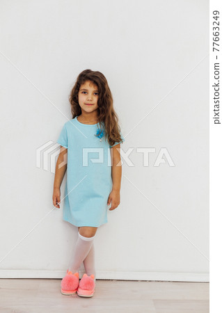Beautiful little curly girl 5 years old in a blue dress on a white background 77663249