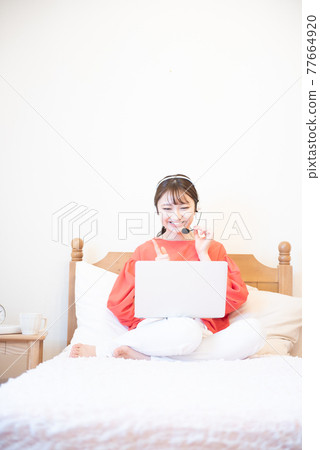 Bedroom laptop young woman 77664920