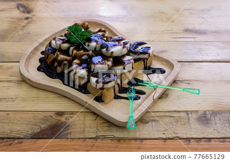 Toasted bread topped with sliced bananas and topped with chocolate sauce. 77665129