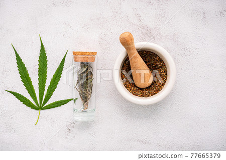 Glass bottle of cannabis oil with white mortar and hemp leaves set up on concrete background. Glass bottle of cannabis oil with white mortar and hemp leaves set up on concrete background. 77665379