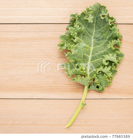 Fresh organic curly kale leaves flat lay on a wooden table with copy space. 77665389