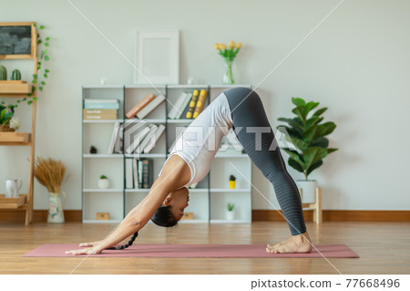 Calm of Beautiful Attractive Asian woman practice yoga Downward Facing dog or yoga Adho Mukha Svanasana pose to meditation with yoga in bedroom,Recreation in holidays concept 77668496