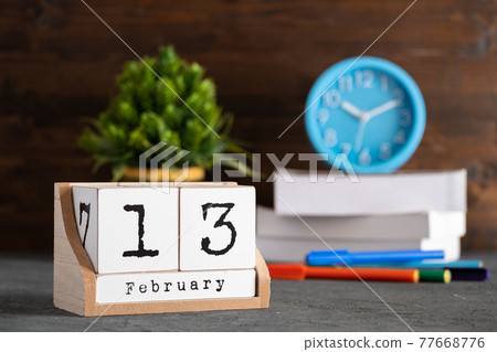 February 13th. February 13 wooden cube calendar with blur objects on background. February 13th. February 13 wooden cube calendar with blur objects on background. 77668776
