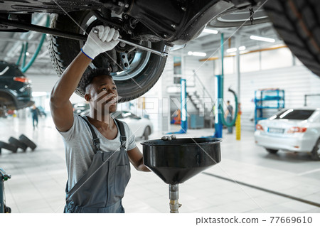 Male mechanic drains the oil, car service 77669610