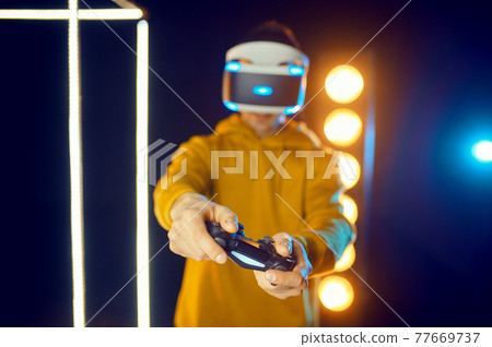 Man using virtual reality helmet and gamepad 77669737