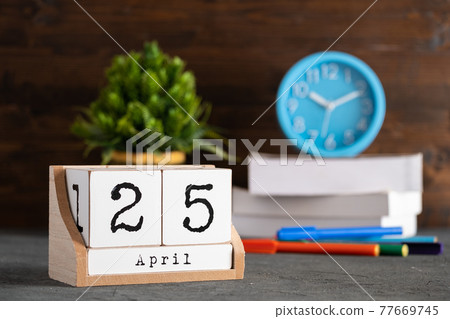 April 25th. April 25 wooden cube calendar with blur objects on background. April 25th. April 25 wooden cube calendar with blur objects on background. 77669745