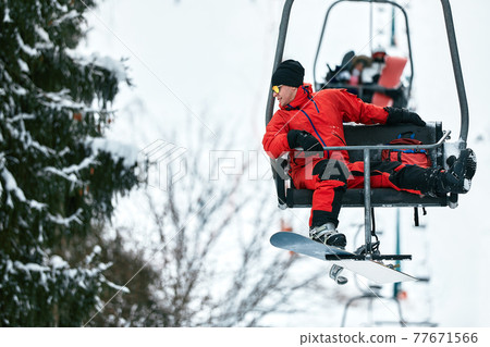 Skier sitting at ski lift talking on the phone in high mountains during sunny day. Winter sport and recreation, leisure outdoor activities. Skier sitting at ski lift talking on the phone in high mountains during sunny day. Winter sport and recreation, leisure outdoor activities. 77671566