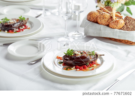 Half baked eggplants with meat, cheese and tomatoes on white background. Banquet festive dishes. Gourmet restaurant menu. White background. 77671602