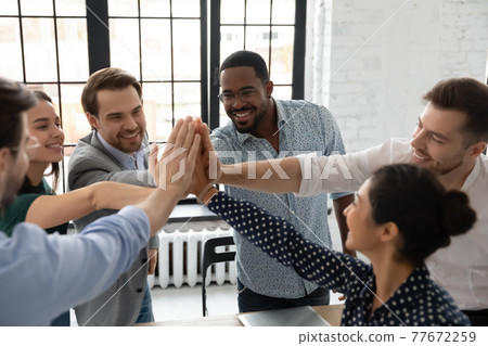 Excited millennial teammates joining hands for giving high fives Excited millennial teammates joining hands for giving high fives 77672259