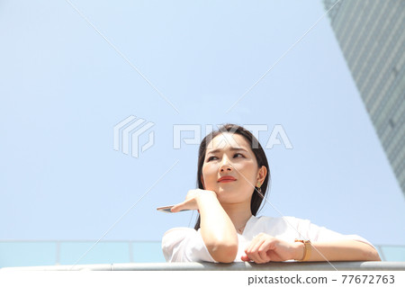 Cute woman looking up blue sky back Cute woman looking up blue sky back 77672763
