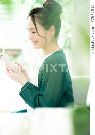 Young woman looking at a smartphone Young woman looking at a smartphone 77675016