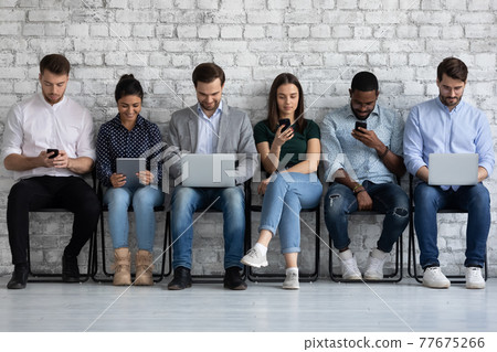 Diverse group of millennial people focused on different devices 77675266