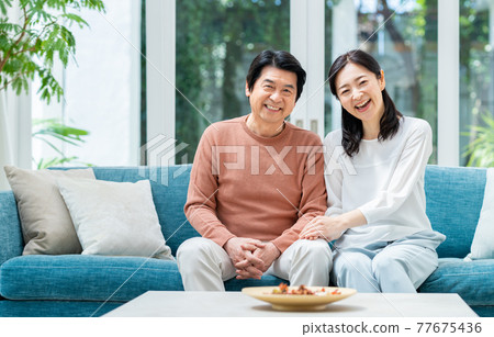 A middle-aged couple relaxing in the living room 77675436