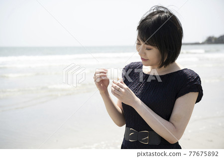 A woman looking at shells picked up on a sandy beach (Shichirigahama, Kamakura City, Kanagawa Prefecture) A woman looking at shells picked up on a sandy beach (Shichirigahama, Kamakura City, Kanagawa Prefecture) 77675892