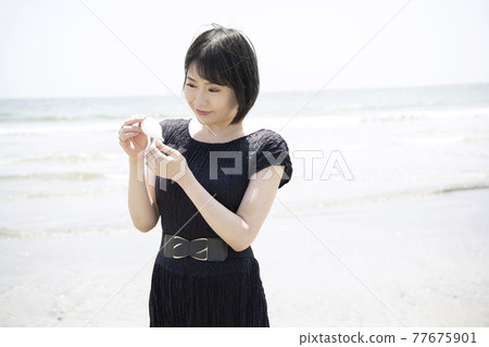 A woman looking at shells picked up on a sandy beach (Shichirigahama, Kamakura City, Kanagawa Prefecture) A woman looking at shells picked up on a sandy beach (Shichirigahama, Kamakura City, Kanagawa Prefecture) 77675901