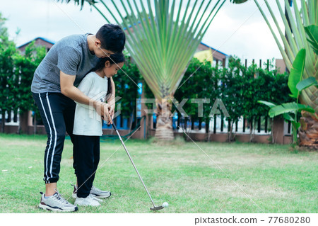 Asian father and giving young daughter golf lesson. Asian father and giving young daughter golf lesson. 77680280