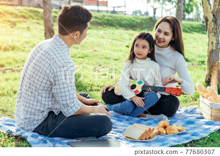 Happy asian family in the garden They play ukulele, singing, take pictures by film camera, eat together and have fun. Happy asian family in the garden They play ukulele, singing, take pictures by film camera, eat together and have fun. 77680307