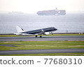 Passenger plane taking off from Haneda Airport-Cargo ship in the background 77680310