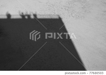 Shadows of people waving from the rooftop of a building 77680503