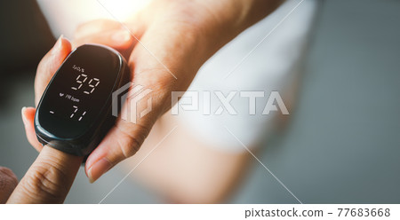 Hand of asian woman with an attached pulse oximeter on fingertip, checking oxygen saturation level in the blood,diagnosis of Coronavirus or COVID-19 at home,health care Hand of asian woman with an attached pulse oximeter on fingertip, checking oxygen saturation level in the blood,diagnosis of Coronavirus or COVID-19 at home,health care 77683668