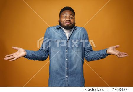 Young african american man shrugging his shoulders, he doesn't know 77684824