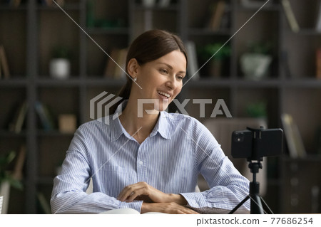 Happy young lady vlogger broadcast live from home using cell 77686254